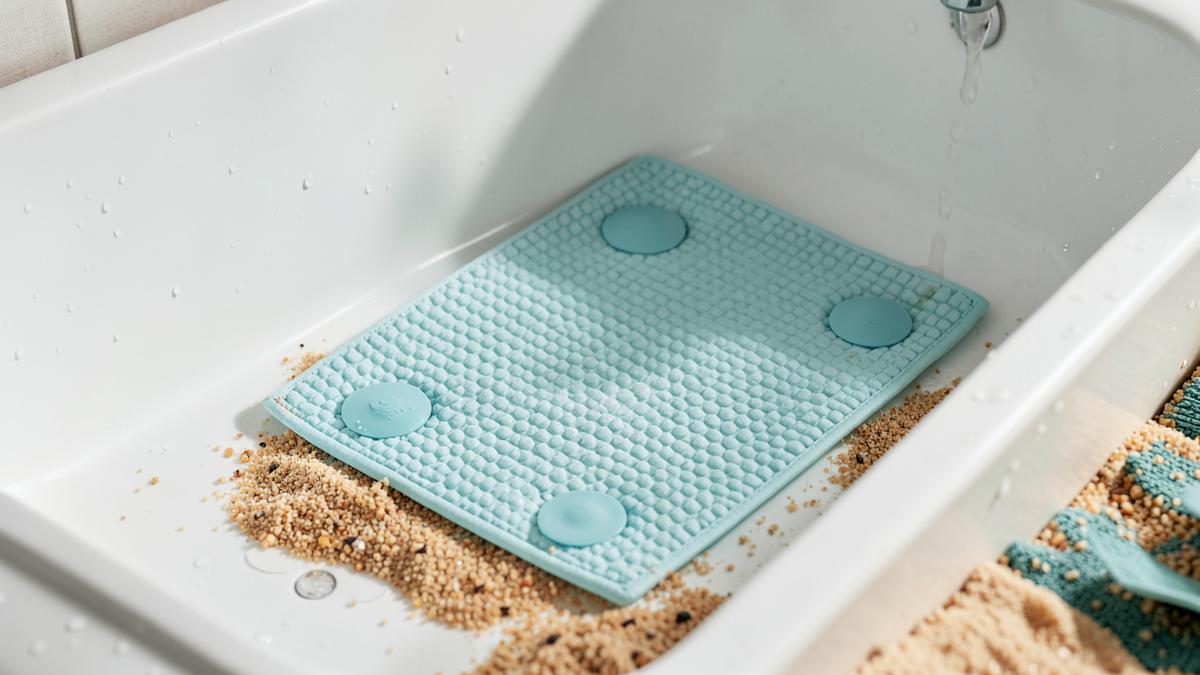 Textured non-slip bath mat with suction cups on the floor of a clean white bathtub